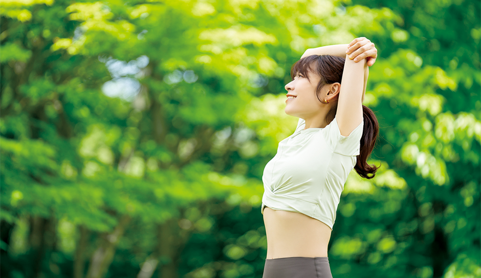 自然の緑の中でストレッチする若い女性